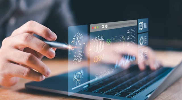 Close-up of a person using a stylus on a laptop with a transparent digital CRM interface displaying customer data, analytics, charts and business management icons. | SUNZINET Customer Platform Agency