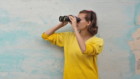 A woman looking into the distance with binoculars as symbol for Revenue Lifecycle Management | SUNZINET